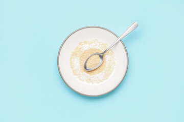 Plate and spoon with amaranth seeds on color background