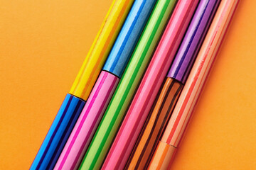 Set of colorful pencils on orange background, closeup