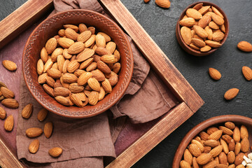 Composition with bowls of almond nuts on dark background, closeup