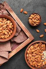 Composition with bowls of almond nuts on dark background, closeup