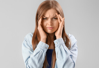 Young woman suffering from loud noise on grey background, closeup