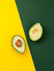 Organic avocado with seed, avocado halves and whole fruits on yellow and green background. - 569324845