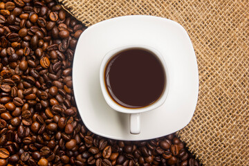 Coffee break background. Hot coffee in cup and roasted coffee beans on a wooden table. Copy space