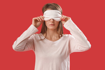 Beautiful woman with sleeping mask on red background