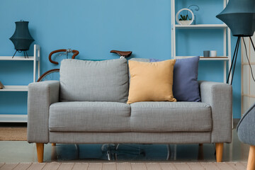 Cozy grey sofa with cushions in interior of room
