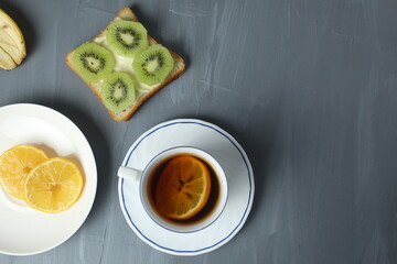 breakfast with sandwiches tea with lemon sandwich with kiwi fruit on a gray background with space for copyspace text. Healthy food breakfast snack tea break