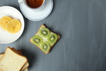 breakfast with sandwiches tea with lemon sandwich with kiwi fruit on a gray background with space for copyspace text. Healthy food breakfast snack tea break