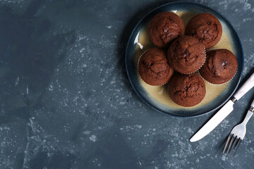 Plate with delicious chocolate muffins on grey grunge background