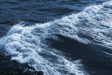 Sea wave with white foam on deep blue water, natural background