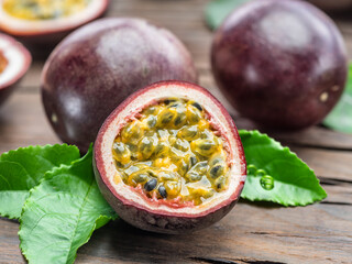 Purple passion fruit with seedly yellow flesh interior on wooden table.