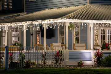 House front yard with big porch brightly illuminated with christmas decorations. Outside decor of...