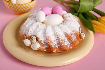 Plate with sweet Easter cake and eggs on pink background, closeup