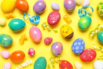 Composition with painted Easter eggs and serpentine on yellow background