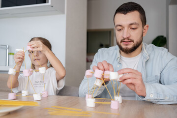 Child and father molecular model with spaghetti and marshmallow learning remotely at home, STEM...