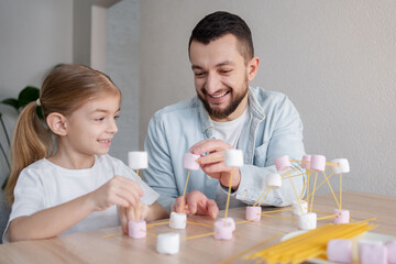 Child and father molecular model with spaghetti and marshmallow learning remotely at home, STEM...