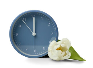 Alarm clock with beautiful tulip flower on white background