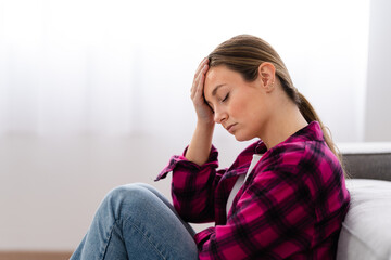 Sad despaired young woman thinking on future while sitting at home