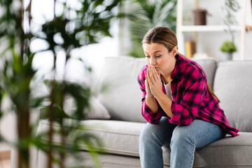 Sad woman sitting on sofa thinking on problems at home. Depression, stress, anxiety and mental health concept.