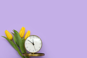 Alarm clock with yellow tulip flowers on lilac background