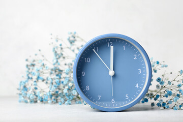 Obraz na płótnie Canvas Alarm clock and beautiful gypsophila flowers on light background