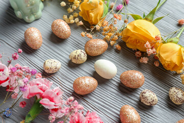 Composition with beautiful Easter eggs and flowers on grey wooden background, closeup