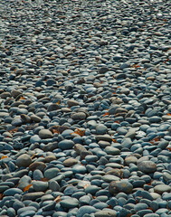 Smooth gray and brown stones along the shore of a lake.
