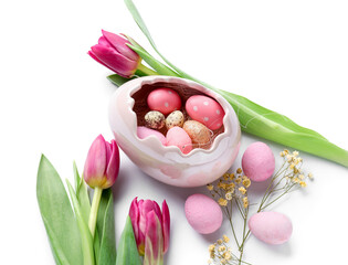 Bowl of beautiful Easter eggs and flowers on white background