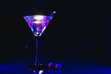 Glass of classic dry martini cocktail with olives on dark table against black background. With free space for your text
