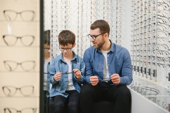 Dad And Son Choose New Stylish Glasses In An Optical Store. Vision Care Concept