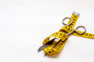 Tijera abiertas envuelta en un metro amarillo sobre un fondo blanco.