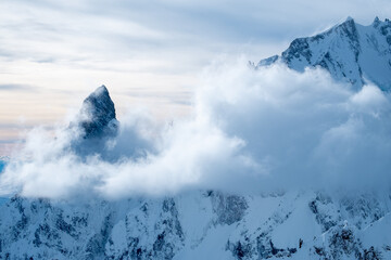 Mountains covered with snow and clouds. The mountains are the Italian Alps