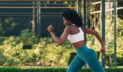 bella mujer negra saludable entrenando y corriendo en un parque al atardecer.