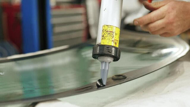 Worker applying an adhesive sealant to car windscreen preparing for replacement. High-quality 4k footage