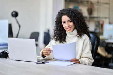 Young smiling latin business woman manager accounting analyst checking bills, analyzing sales...