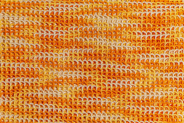 Texture is crochet from a synthetic cord of autumn-like colors. Repeating net texture crocheted from a polyamide cord of orange, white and yellow colors.
