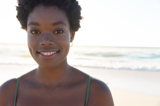 Close-up Of Smiling African American Young Woman With Afro Short Hair Over Sea And Sky At Sunset