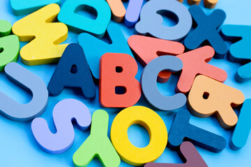 Colorful wooden alphabets on blue background.