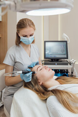 Female is getting cleaning, lifting, rejuvenation, moisturizing face treatment in beauty clinic.