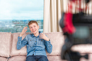 beautiful happy boy teenager making video blog for social networks in living room influencer...