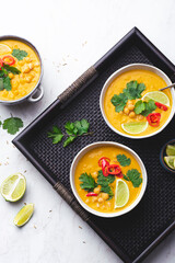Light orange veggie curry with chickpeas, chili peppers, coriander leaves and cumin seeds on a wicker ethnic tray. Vegetarian recipes, healthy food Fusion cuisine