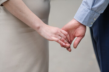 The boy and the girl walk holding hands. Man holding woman's hand