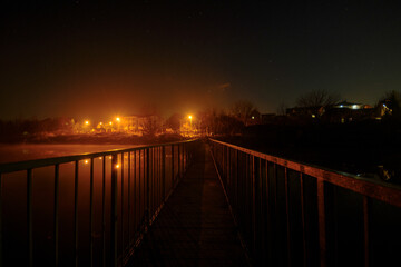 Bridge over a large river, starry sky, warm lights of the city
