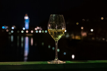 Tasting of french sparkling white wine with bubbles champagne outdoor at night with view on Marne river and lights of Epernay city in winter