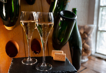 Glasses of sparkling white wine champagne or cava with bubbles and classic wooden champagne pupitre rack with empty bottles on background