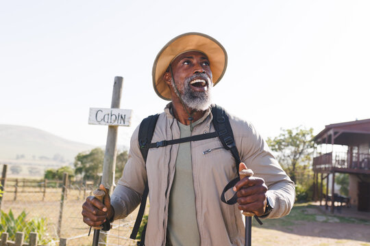 Surprised African American Senior Man With Hiking Poles Walking On Land Against Clear Sky