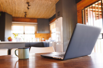 Laptop with coffee mug on wooden table in log cabin