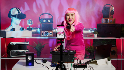 Musician performing techno song recording music session with smartphone camera, interacting with fans during performance. Artist mixing stereo sounds with electronics using professional mixer console