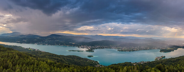 Sunset panorama Lake Worthersee in Austria. On the right a small piece of a rainbow after a rain shower