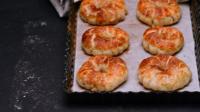 ready-made pastries on a baking sheet are placed on the black table of the kitchen. baking sheet in hand with a towel. Slow motion. High quality 4k footage