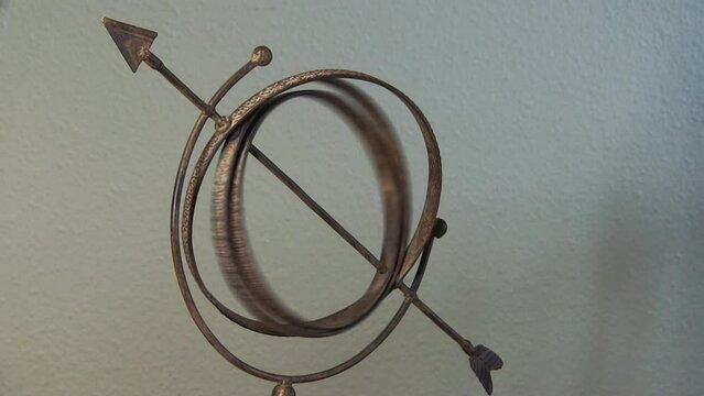 Metal Ornament With Arrow And Two Rings Spinning Together And Coming To A Stop
